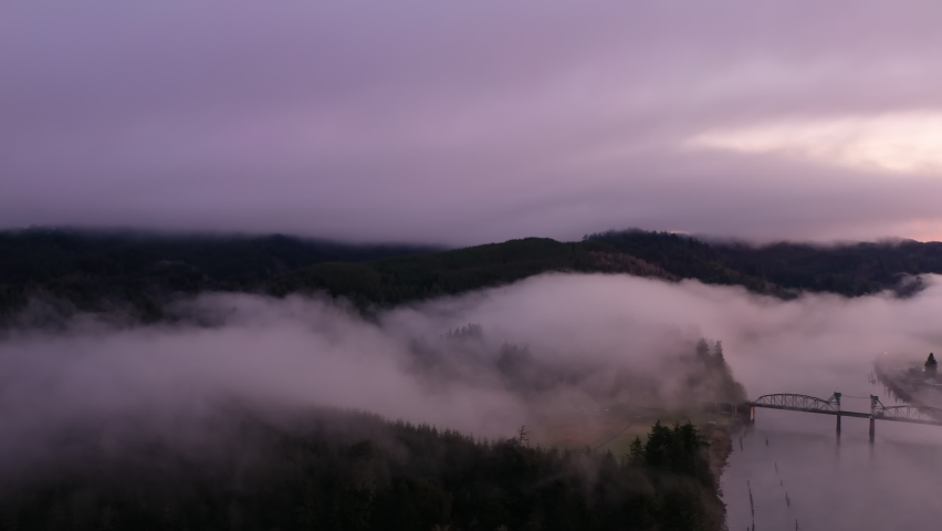 Dramatic Oregon sunrise over Coos River and bridge. Drone panning shot