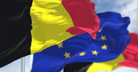 Seamless slow motion loop of the national flag of Belgium waving in the wind with blurred european union flag in the background on a clear day. Democracy and politics. European country. 