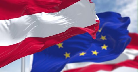 Seamless slow motion loop of the national flag of Austria waving in the wind with blurred european union flag in the background on a clear day. Democracy and politics. European country. 