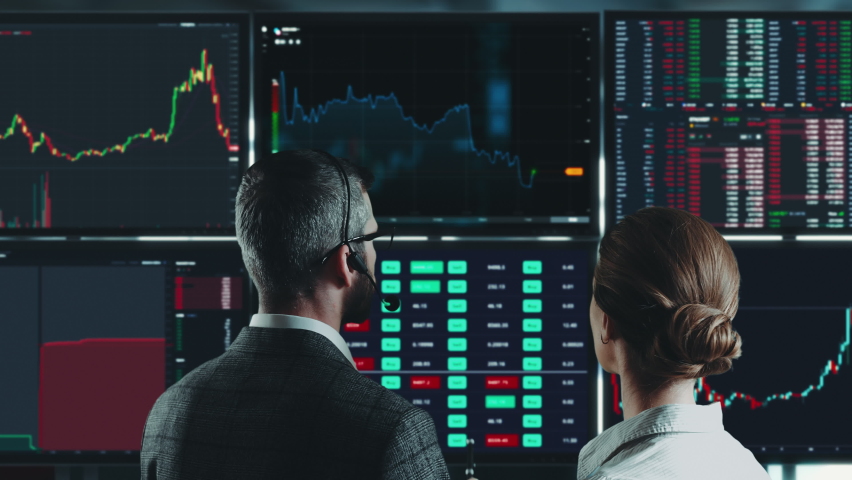Colleagues traders analysts are working with multiple computer screens full of charts and data analysis and stock broker trading online. Back view. Concept of bitcoin and stock market trading. Royalty-Free Stock Footage #1089768791