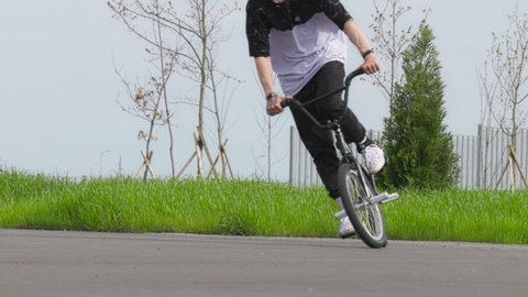 BMX Flatland bicycle rider performing a trick: Pedaling Time Machine No Hand. BMX Freestyle on Flatland. A young man doing a spinning trick on a bmx bike. 120 fps, ProRes 422, 10 bit video