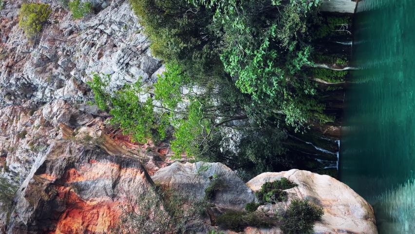 Small mountain lake with tranquil clear water surrounded by bare rocky hills. Majestic nature landscape. Beautiful wild nature. Green rocky slopes and mountain river. Travel adventure concept