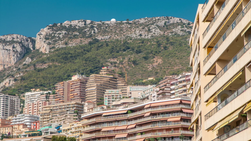 Monaco, Monte Carlo architecture on mountain hill background timelapse. Many multi-story houses, buildings. Summer sunny day