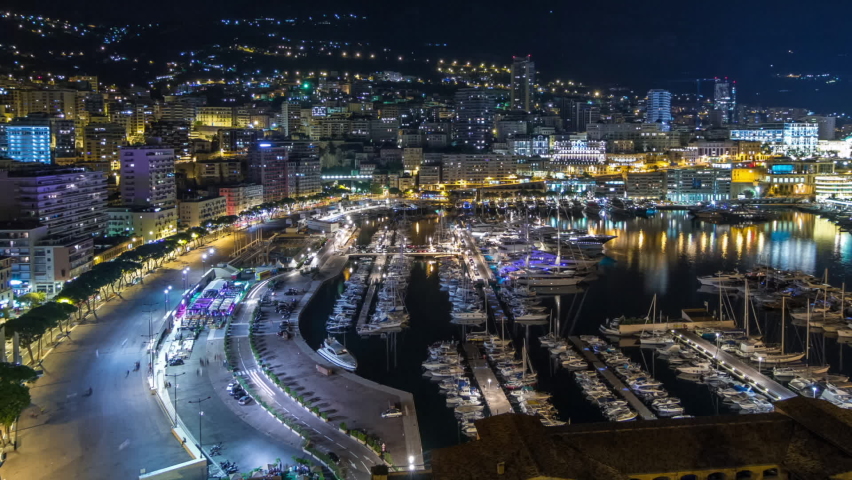 Panorama of Monte Carlo timelapse hyperlapse at night from the observation deck in the village of Monaco with Port Hercules. Buildings with illumination and yachts in harbor aerial top view. Traffic