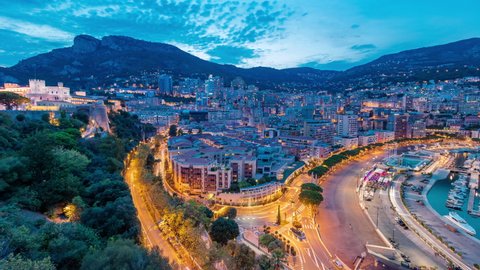 Panorama of Monte Carlo day to night transition timelapse from the observation deck in the village of Monaco near Port Hercules. Buildings with illumination and hills on background aerial top view