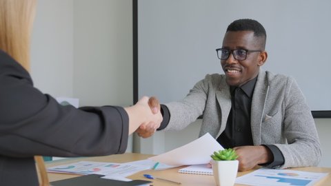 African black man shake hands with his business partner caucasian woman. Handshake when got agreement, deal or signed contract. Diverse business people of different ethnicity and gender.