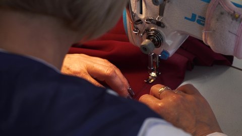 girl sews a dress on a sewing machine. 4k footage of a seamstress.A woman working on a sewing project as she cuts fabric and sews it on a machine. sewing machine close up