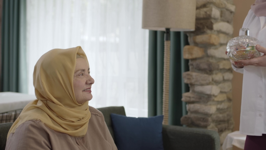 A woman wearing a headscarf, traditionally offering candy to her mother to celebrate Eid-al-Adha after the end of the holy month. Eid tradition in Muslims. Royalty-Free Stock Footage #1089772999