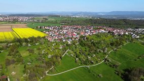 Aerial footage of reverse flight over rural landscape with small village and green meadows in spring in Southern Germany