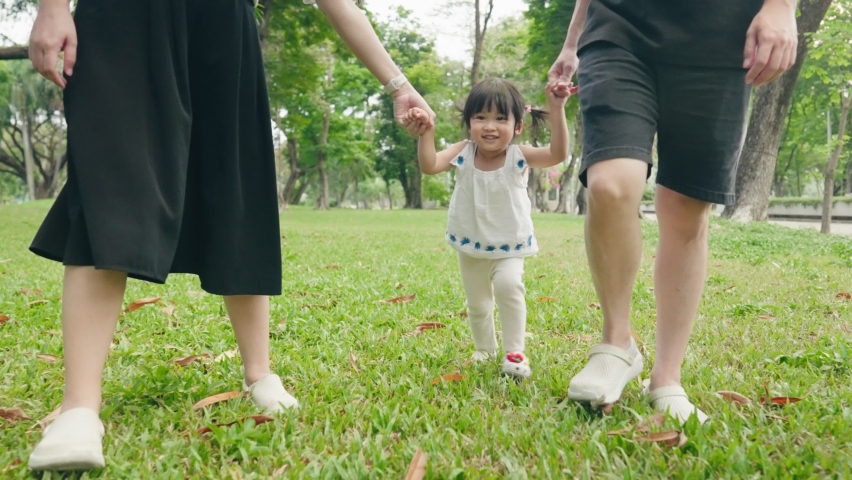 Asian mom dad and daughters walk holding hands in the park. happy family kid dream concept. parents and fun children walking front view, playful girl walking in the middle holding parents hands Royalty-Free Stock Footage #1089778975