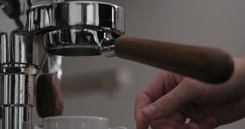 Slow motion low angle shot of rinsing water from naked portafilter