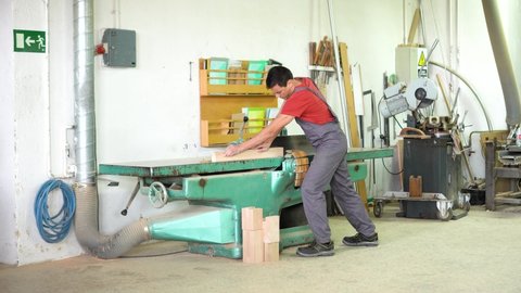 Carpenter working at woodworking planer in workshop