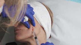 woman undergoing rejuvenating facial mesotherapy treatment with vitamins and hyaluronic acid injected with a cannula