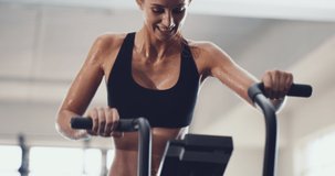 Shes working up a sweat. 4k video of an attractive young woman working out on an exercise bike in the gym.