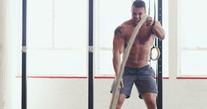Pushing his body to the max. 4k video of a muscular young man working out with heavy ropes at the gym.