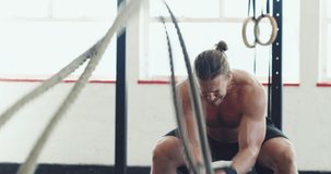 Work those muscles like never before. 4k video of a muscular young man working out with heavy ropes at the gym.