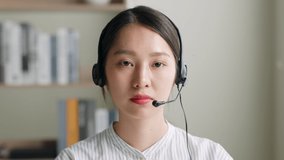 POV of Young Asian woman wearing headset talking on video call or virtual meeting, front view, look at camera