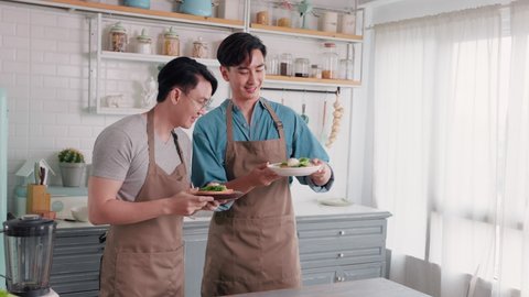 Asian gay couple tease each other very happy and romantic in their home kitchen while cooking for healthy together. The food is lovely to eat and has a seductive aroma. People LGBTQ lifestyle