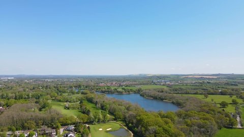 Aerial video of Coate Water Country Park, Swindon, Wiltshire, revealing the beauty of the park, its attractions such as the golf course and its beautiful lake on a sunny day