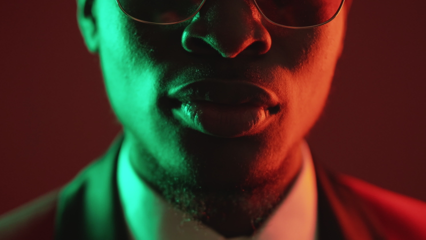 Shush gesture. Man secret. Keep quiet. Closeup of unrecognizable gentleman showing shh with finger on lips in green neon light isolated on dark red. Royalty-Free Stock Footage #1089790289