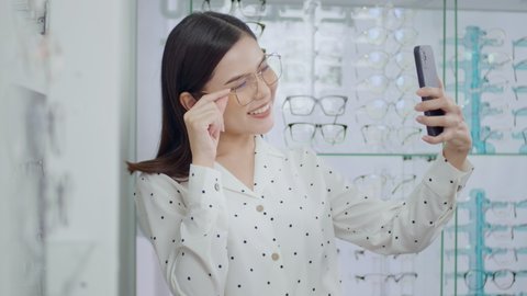 Young female customer trying on glasses and taking a selfie in optical center, Eye care concept.

