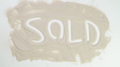Sold out. Top view draw on the sand. Caucasian hands write text in beige sand. Vacation and travel. Beach on vacation. Sand painting. Creativity from natural materials.