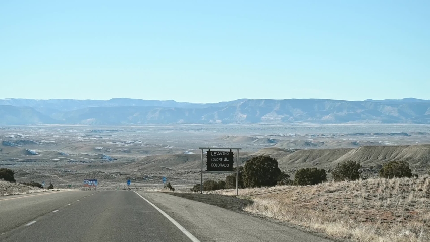 Driving on I-70 past the leaving colorful Colorado state line sign