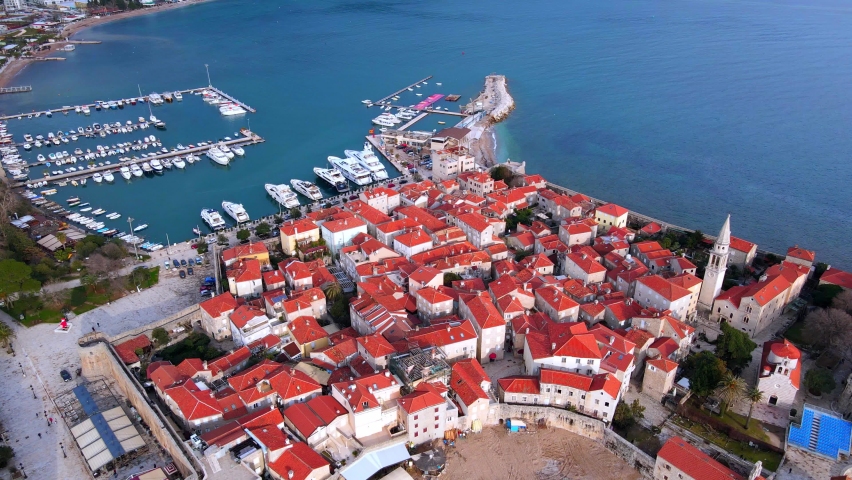 Budva Montenegro old Mediterranean town with red roofs on white medieval stone houses featuring church bell tower. Aerial drone view tourist destination. Drone Shot of old town Budva in Montenegro