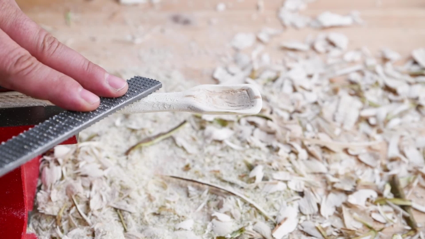 Footage of a wooden spoon carving with wood rasp on a workbench with wood chips, Germany