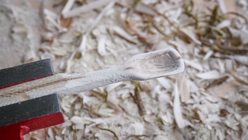 Footage of a wooden spoon carving with sandpaper on a workbench with wood chips, Germany