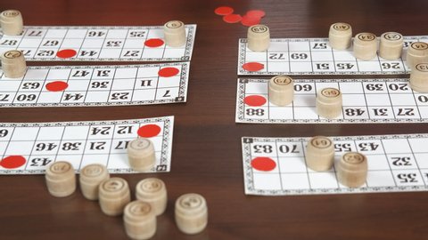 Play with barrels with numbers. Two friends play with barrels with numbers on the bingo cards on the table.