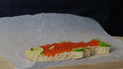 Sandwich with red caviar in shape of fish with lemon put on table. Expensive healthy food concept close-up slow motion. Sandwiches bread  toast with salmon caviar salted roe. Fish dish. Sea food