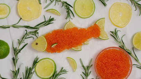 Sandwich with red caviar in shape of fish with lemon, rosemary rotate. Expensive healthy food concept on white background. Sandwiches bread toast with salmon caviar salted roe rotating slow motion