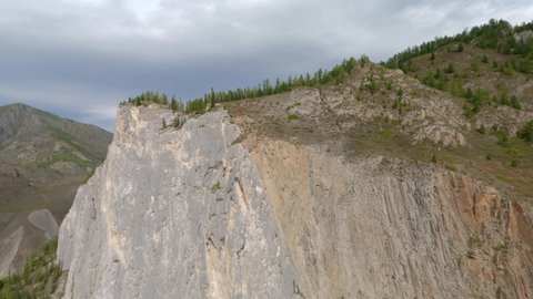 Aerial view flying natural cliff top of white marbled limestone rising above river wild summer picturesque landscape. FPV sports drone nature mountain peak valley forest scenery cloudscape horizon 4k