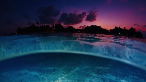 Night sea with island. Underwater splitted view of the tropical calm sea and island during late twilight