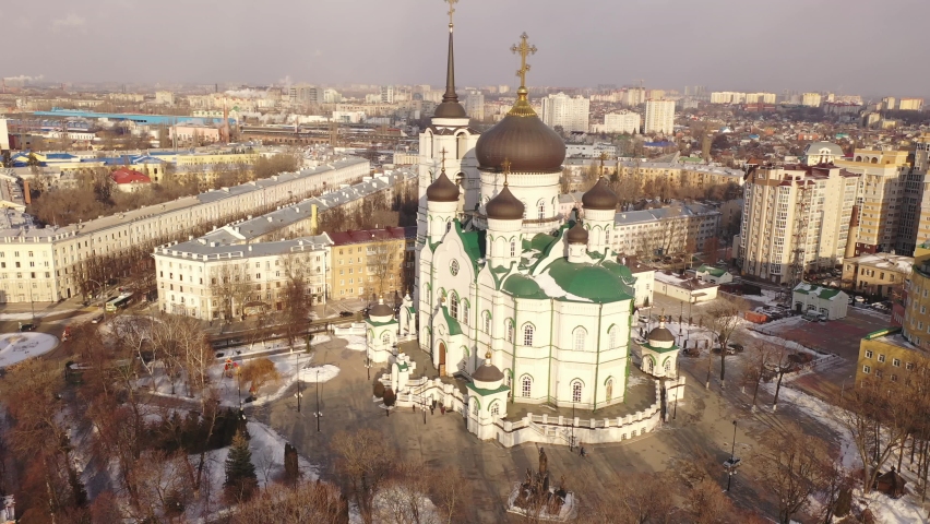 Aerial view of five-domed building of Annunciation Cathedral with attached bell tower in Voronezh on background with winter cityscape, Russia Royalty-Free Stock Footage #1089807769
