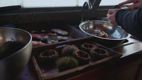 close-up of male hands. A man prepares sea delicacies. Cooking sea urchins and oysters. Cooking. Metal chromed kitchen bowl.