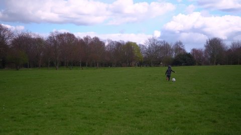 Happy Family Of Children Having Fun In Spring Park. Little Kid Run. Child Boy Dribbles Black White Classic Soccer Ball On Green Grass. People Playing Football. Childhood, Sport, Championship Concept
