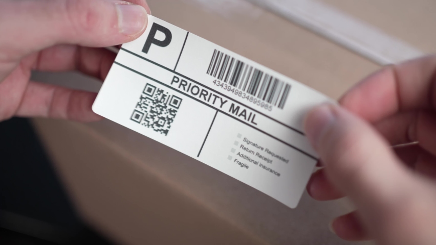 Stocking a shipping label on a cardboard box ready to get shipped in the mail. Closeup shot. Royalty-Free Stock Footage #1089813327