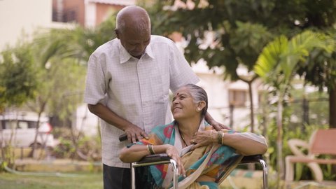 Happy senior man talking his wife during evening walk at wheelchair - concept of happiness, relationship and Bonding Video de stock