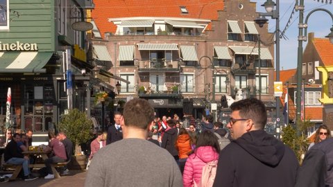 Volendam, The Netherlands - April 18, 2022: Locals and tourists enjoying a sunny day at seaside Volendam boardwalk.