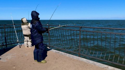 Kaliningrad, Russia, 12, March, 2022:
Fishermen in warm clothes are fishing from the pier in the sea, fishing in the Baltic Sea with a bait