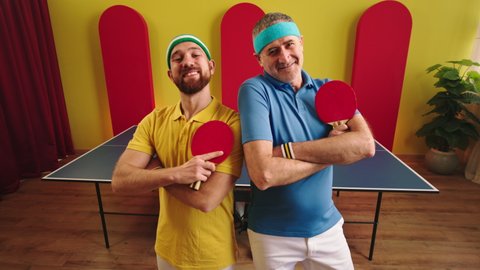 In front of the camera closeup two table tennis players shaking hands after a good game then posing to the camera crossing hands and smiling cute