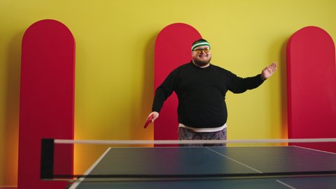 Funny fat guy get ready to play on the ping pong he dancing and moving charismatic all equipment holding the racket on hands