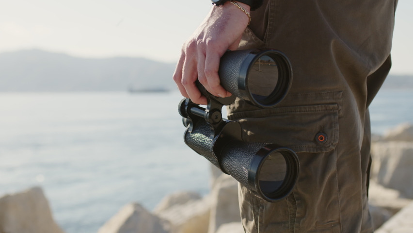 binoculars in hands with sea background