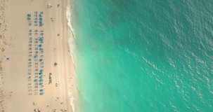 Aerial view of the amazing beach with colorful umbrella and people who relaxing and swimming in clear water of a Mediterranean sea at sunny day.