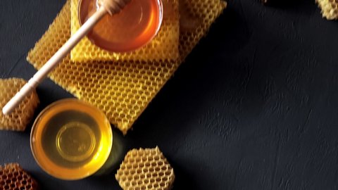 Honey dripping, pouring from a wooden spoon. Liquid fresh golden honey. Honeycombs. Healthy organic honey.