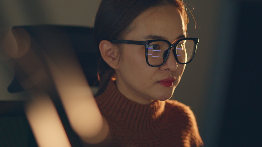Young Asian woman, developer programmer, software engineer, IT support, wearing glasses working hard at night overtime on computer to check coding in bugging system.  | Shutterstock HD Video #1089825717