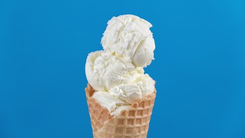 Timelapse of vanilla ice cream in waffle cone melting on blue background. Delicious white ice cream melting. Close-up of sweet dessert. 4K, UHD