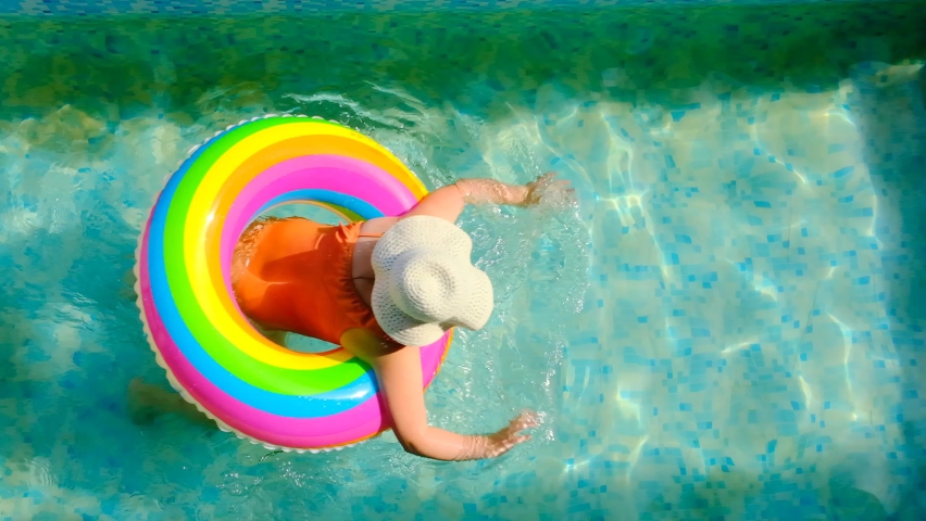 Girl with a rainbow inflatable ring in the pool.Summer time. High quality 4k footage